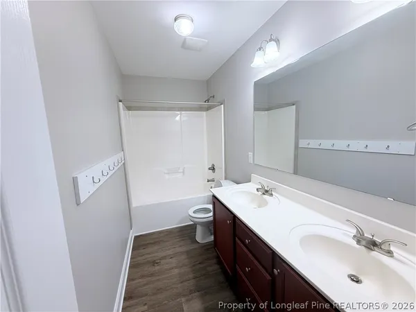 a bathroom with a double vanity sink a toilet a mirror and shower