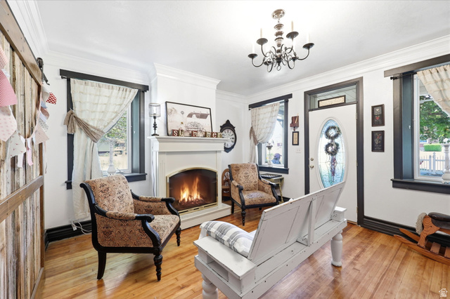 310 South 300 West Payson, UT 84651 - Photo 10 of 42 Living area featuring a classic fireplace, crown molding, wood-finish flooring, a decorative front door with an oval glass insert, and dark framed windows