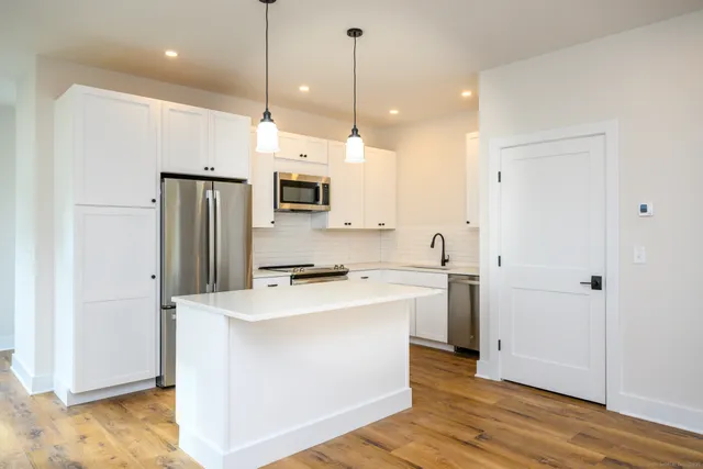 a kitchen with kitchen island a sink appliances and wooden floor