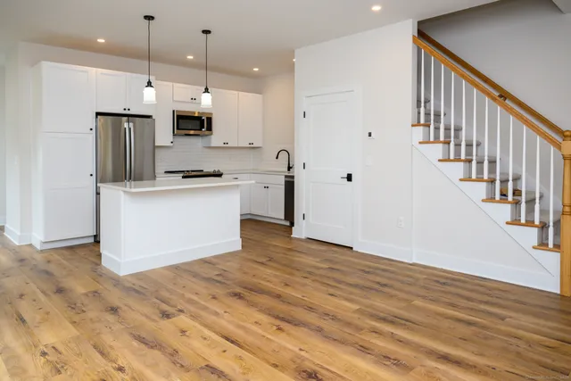 a kitchen with stainless steel appliances a refrigerator and a wooden floor