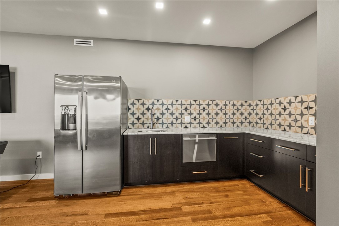 2623 Alum Cave Road Bee Branch, AR 72013 - Photo 49 of 60 Kitchenette featuring wood-finish flooring, dark cabinetry with bar pulls, patterned tile backsplash, and a stainless steel refrigerator