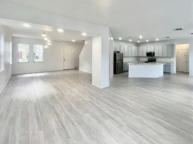 a view of kitchen with kitchen island wooden floor center island and stainless steel appliances
