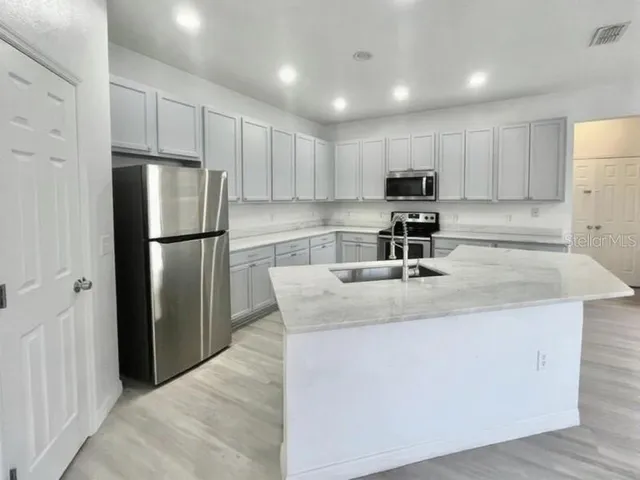 a kitchen with kitchen island a sink stainless steel appliances and refrigerator