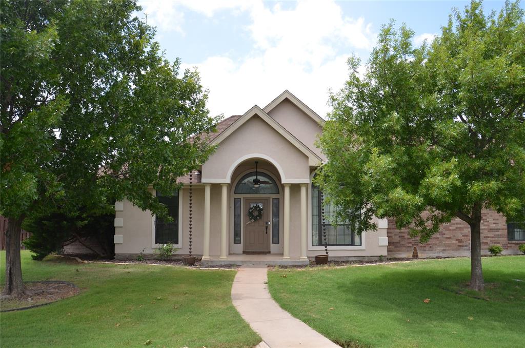 a view of a front of a house with a big yard and large trees