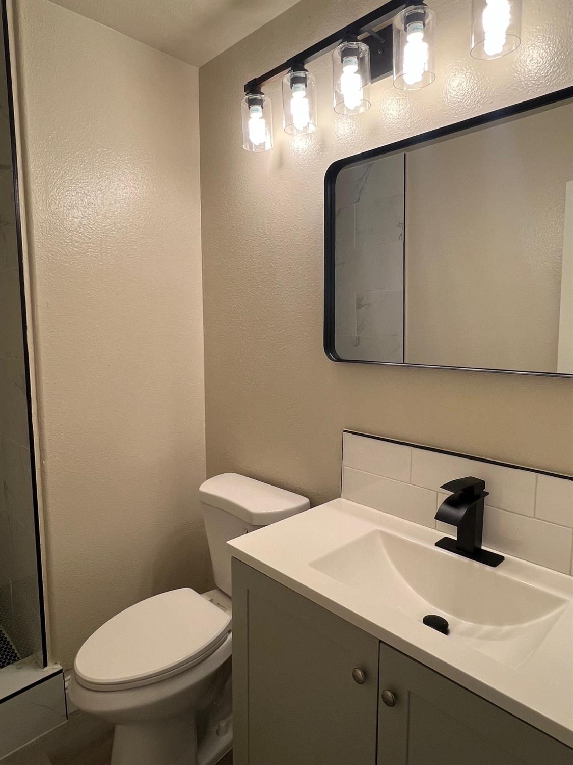 5930 West Birch Avenue Fresno, CA 93722 - Photo 11 of 32 a bathroom with a toilet sink and mirror