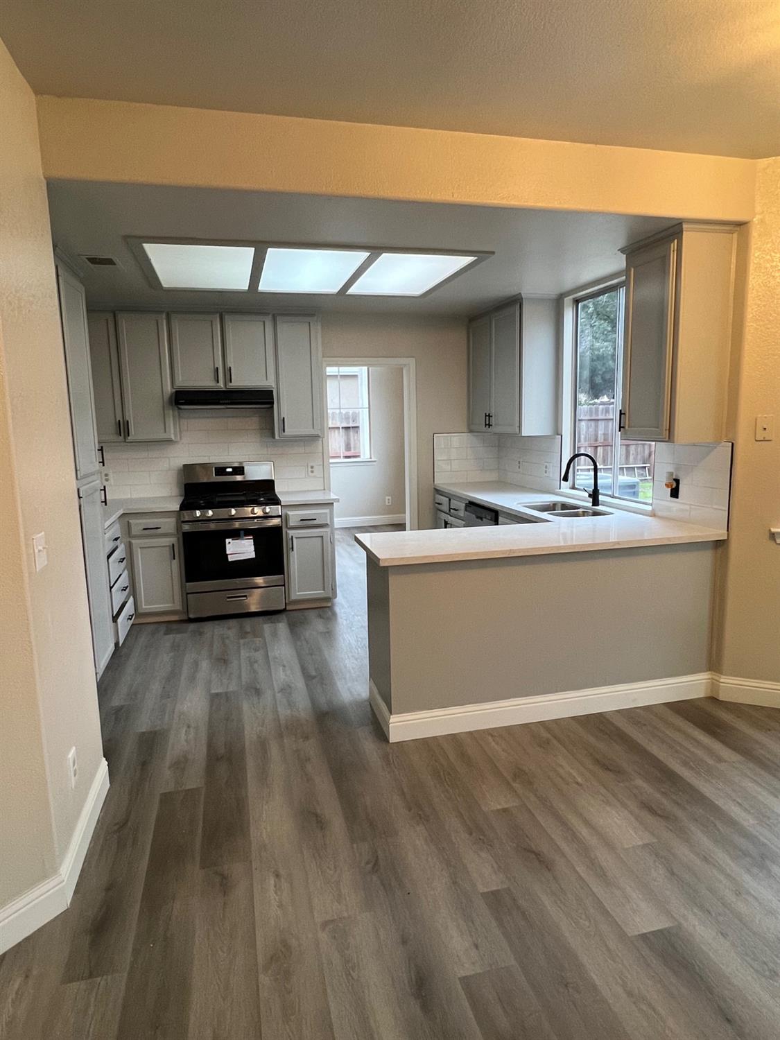 5930 West Birch Avenue Fresno, CA 93722 - Photo 8 of 32 a kitchen with stainless steel appliances a sink a stove a refrigerator cabinets and a dining table