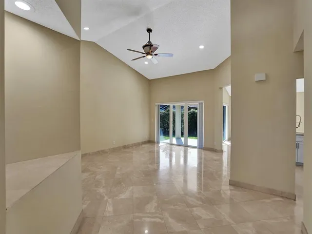 a view of an empty room with window and a ceiling fan