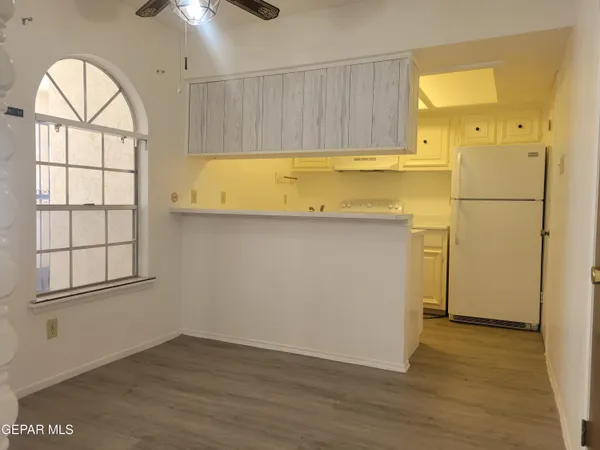 an empty room with wooden floor a ceiling fan and windows