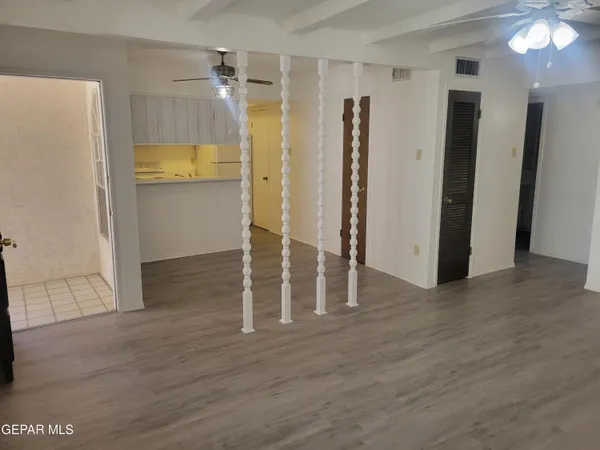 an empty room with wooden floor and a ceiling fan
