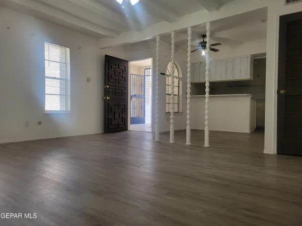 an empty room with wooden floor and windows