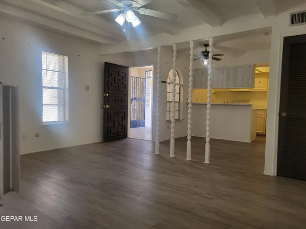 an empty room with wooden floor closet and windows
