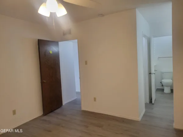 a view of an empty room with wooden floor and a bathroom