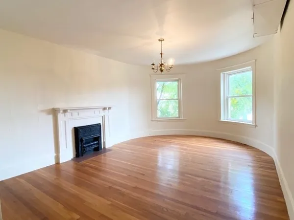 an empty room with windows fireplace and wooden floor