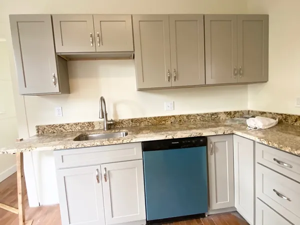 a kitchen with granite countertop white cabinets and sink