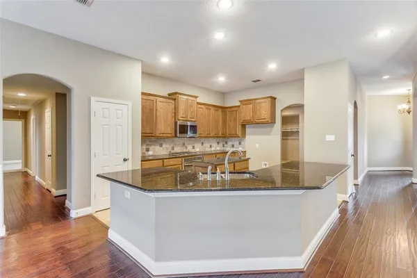 a large kitchen with stainless steel appliances granite countertop a large counter top and a wooden floor