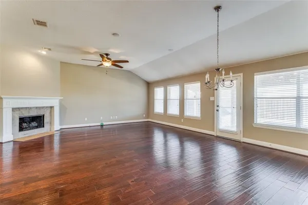 an empty room with wooden floor fireplace and windows