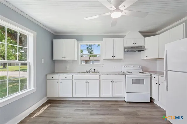 a kitchen with stainless steel appliances a stove a sink and white cabinets