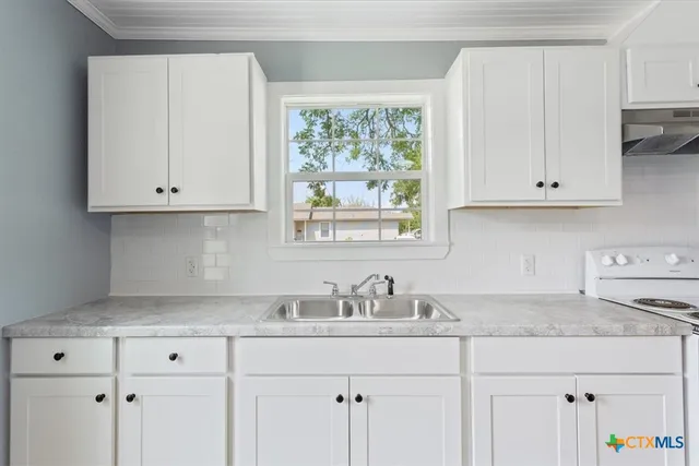 a kitchen with granite countertop white cabinets and a sink