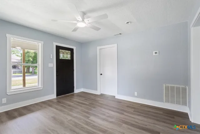 a view of an empty room with a window and wooden floor