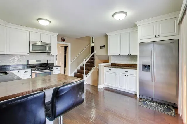a kitchen with kitchen island granite countertop a stove cabinets and wooden floor