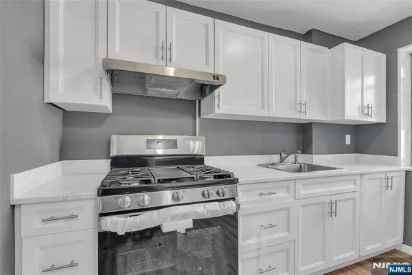 a kitchen with granite countertop a stove sink and cabinets