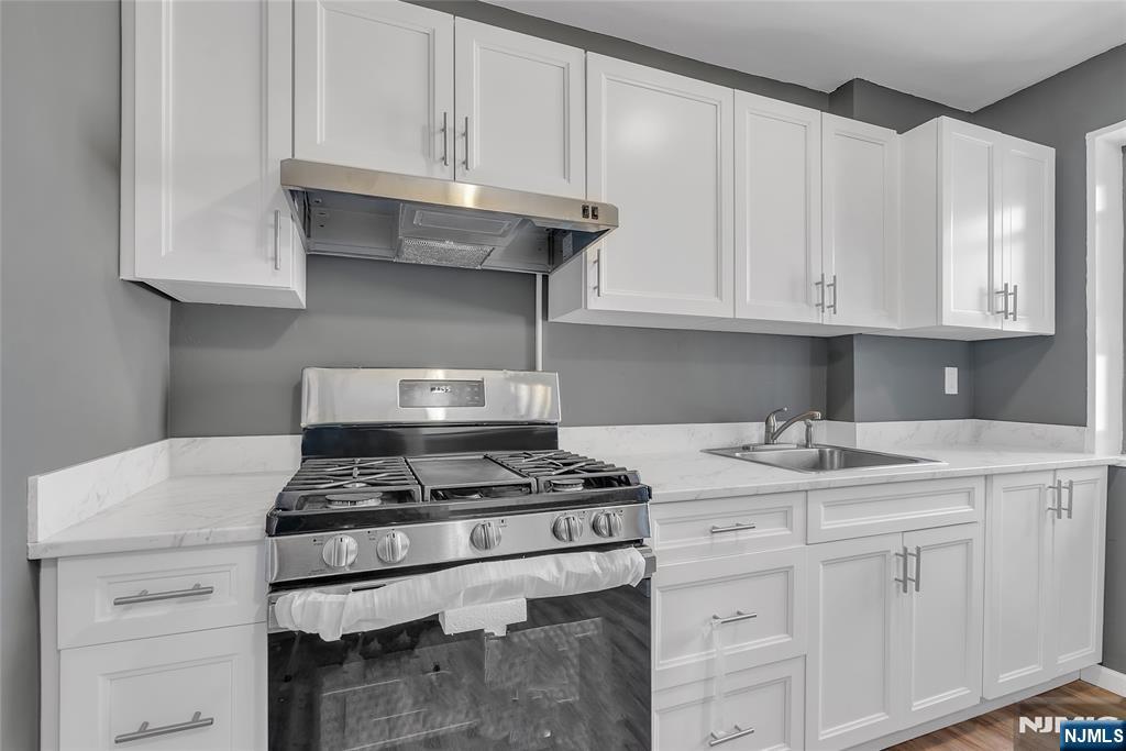 208 Anderson Street, Unit S4C Hackensack, NJ 07601 - Photo 2 of 17 a kitchen with granite countertop a stove sink and cabinets