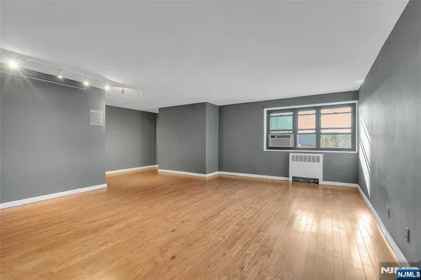 a view of an empty room with wooden floor and a window