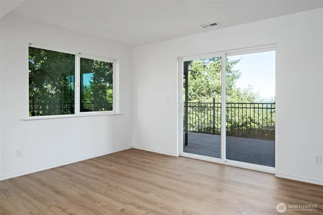 a view of an empty room with wooden floor and glass door