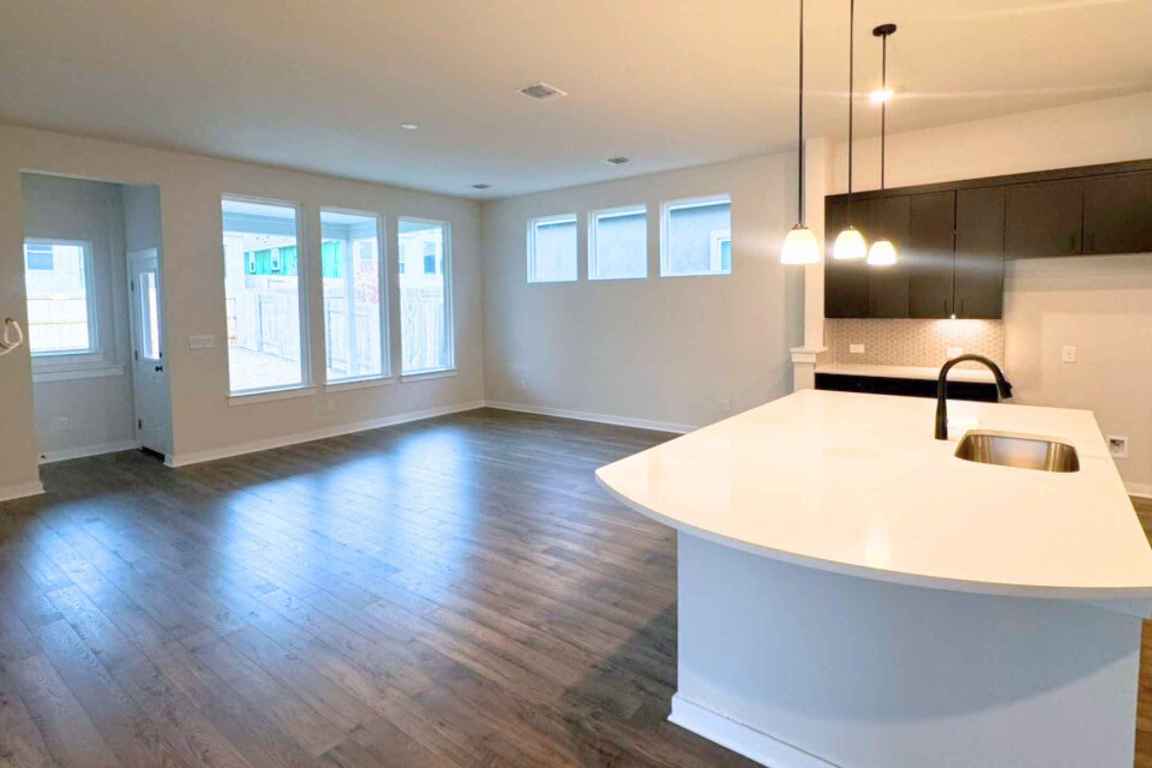 237 Wingstem Way Georgetown, TX 78633 - Photo 20 of 40 Kitchen with decorative light fixtures, dark wood finished floors, a kitchen island with sink, backsplash, and open floor plan