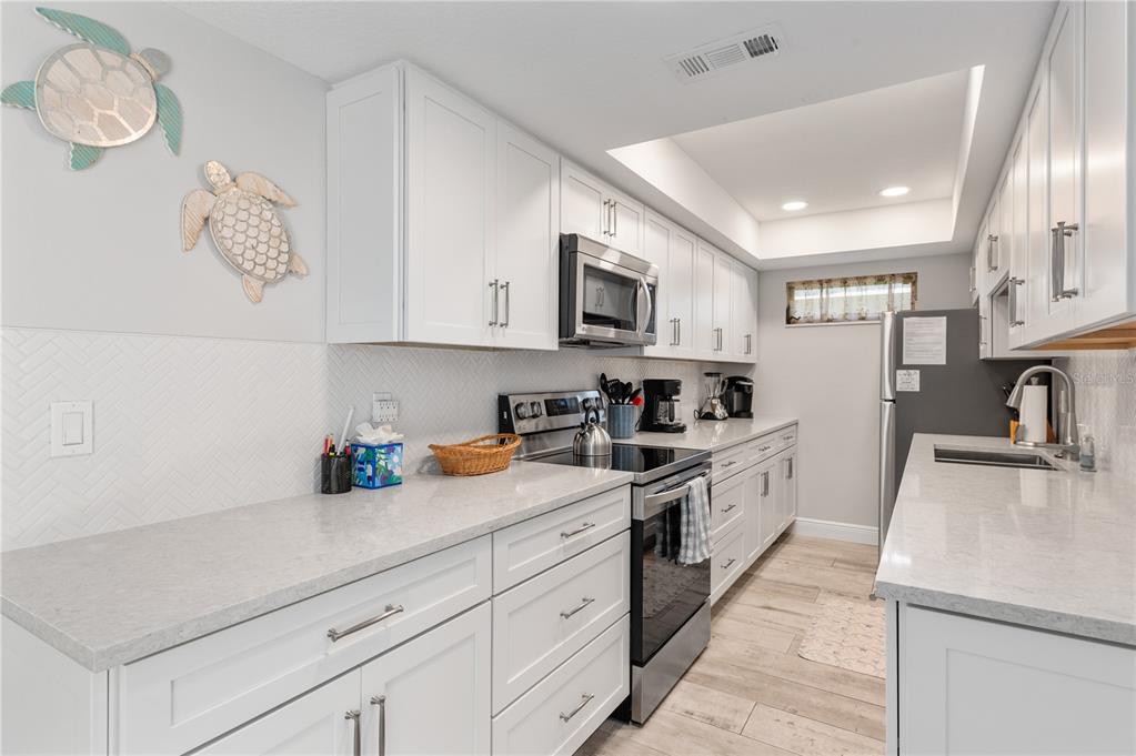 6005 Midnight Pass Road, Unit S4 Sarasota, FL 34242 - Photo 11 of 34 a kitchen with granite countertop white cabinets and white appliances