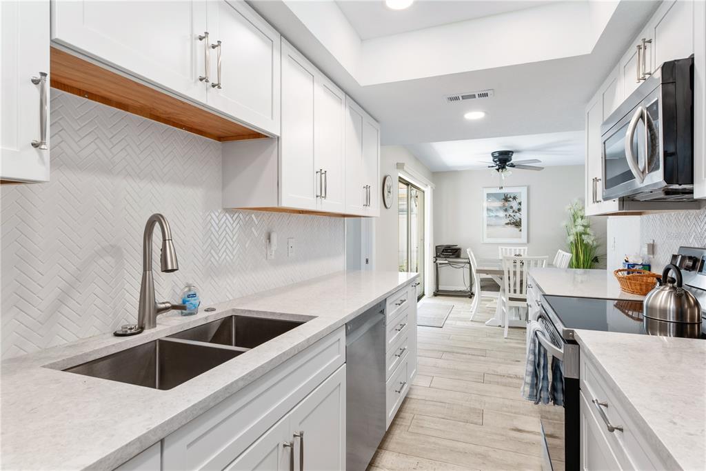 6005 Midnight Pass Road, Unit S4 Sarasota, FL 34242 - Photo 13 of 34 a kitchen with stainless steel appliances granite countertop a sink dishwasher and white cabinets with wooden floor
