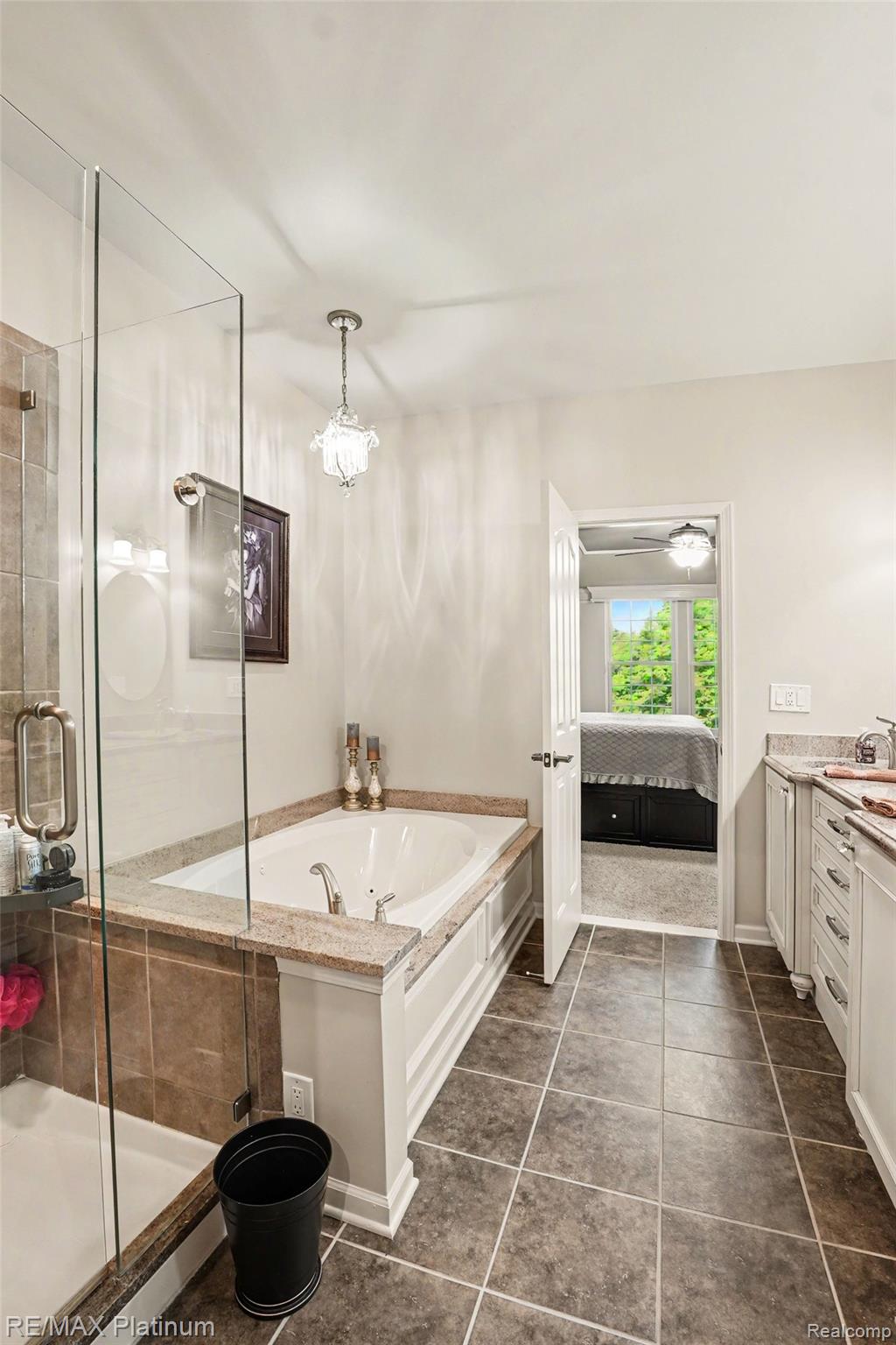609 Telya Ridge Milford, MI 48381 - Photo 13 of 28 Bathroom featuring a built-in soaking tub, glass-enclosed shower, white vanity cabinetry with stone countertops, and square tile flooring