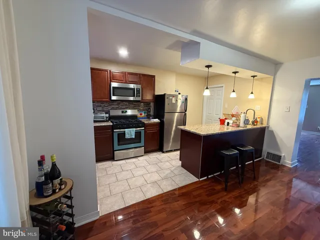 a kitchen with stainless steel appliances kitchen island granite countertop a refrigerator and a stove top oven