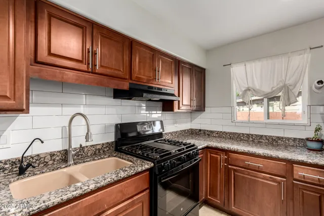 a kitchen with granite countertop a stove sink and cabinets