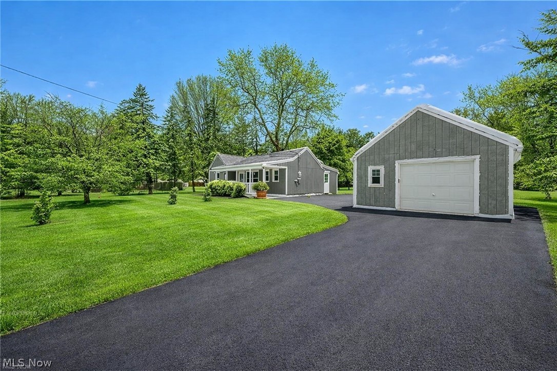 8564 Cedar Road Chesterland, OH 44026 - Photo 2 of 43 The property features a well-maintained lawn, a paved driveway, and a detached garage with a white garage door