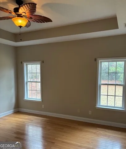 a view of an empty room with wooden floor and window