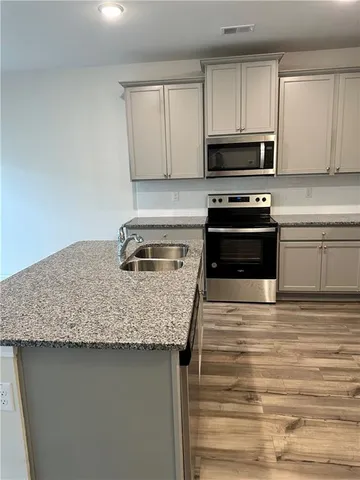 a kitchen with kitchen island a stove microwave and sink