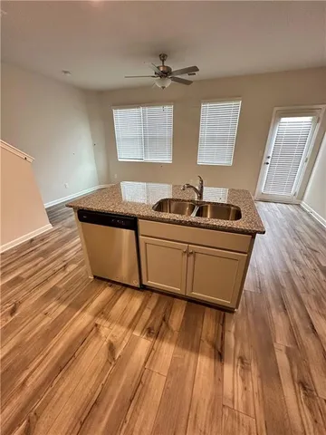 a kitchen with granite countertop a sink and wooden floors