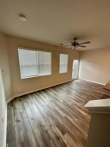 a view of an empty room with a window and wooden floor