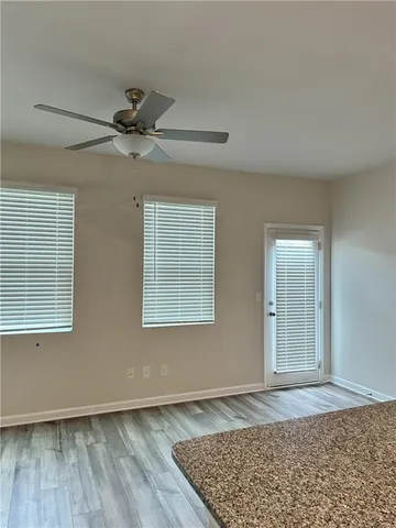 an empty room with wooden floor fan and windows