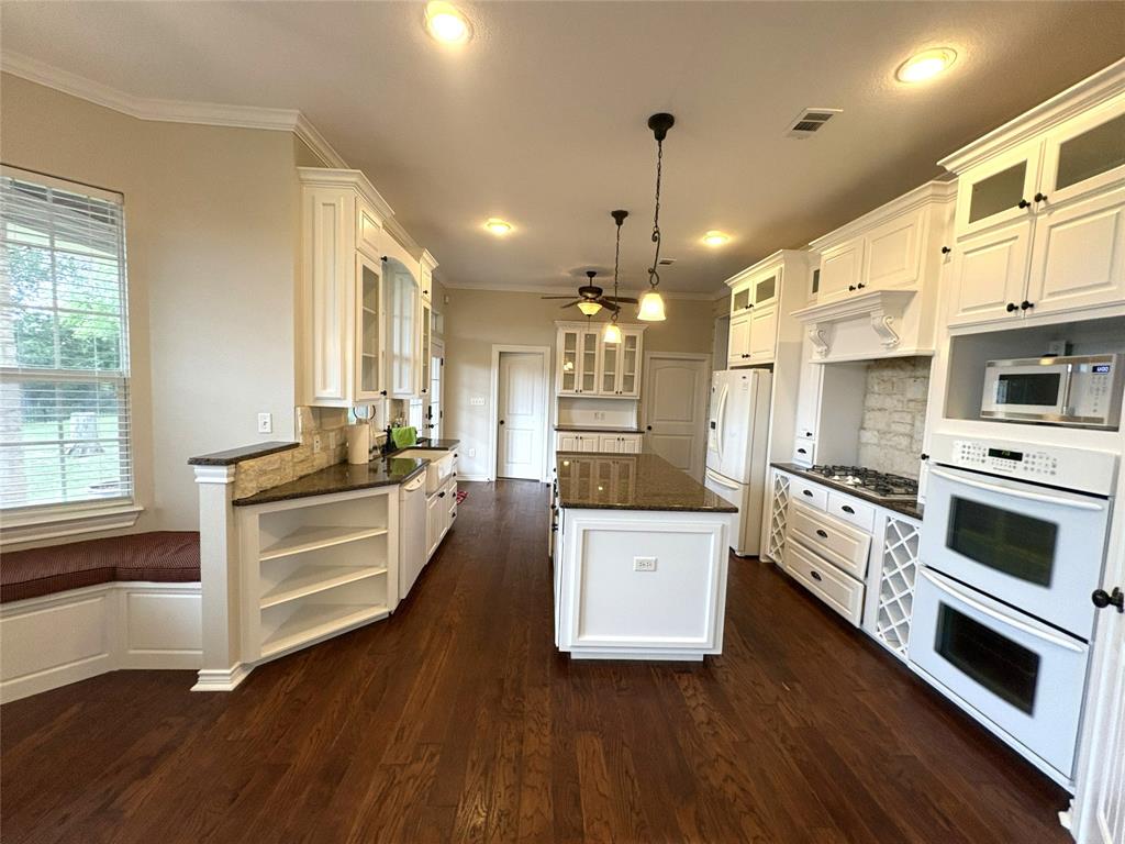 1170 Brazos Loop Gholson, TX 76705 - Photo 19 of 37 Spacious kitchen featuring white cabinetry, dark countertops, wood-finish flooring, a central island, and built-in double ovens