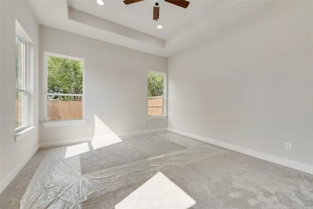 an empty room with windows and ceiling fan