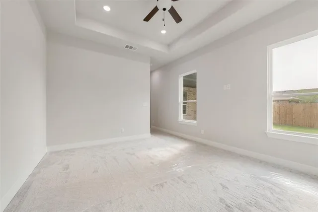 en empty room with windows and ceiling fan