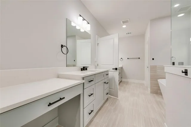 a spacious bathroom with a double vanity sink a mirror and a bathtub