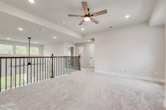 an empty room with ceiling fan and windows