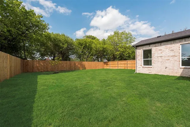 a view of a backyard with grass and a large tree