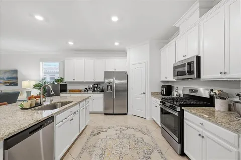 a kitchen with stainless steel appliances granite countertop a stove a sink a microwave a refrigerator and white cabinets