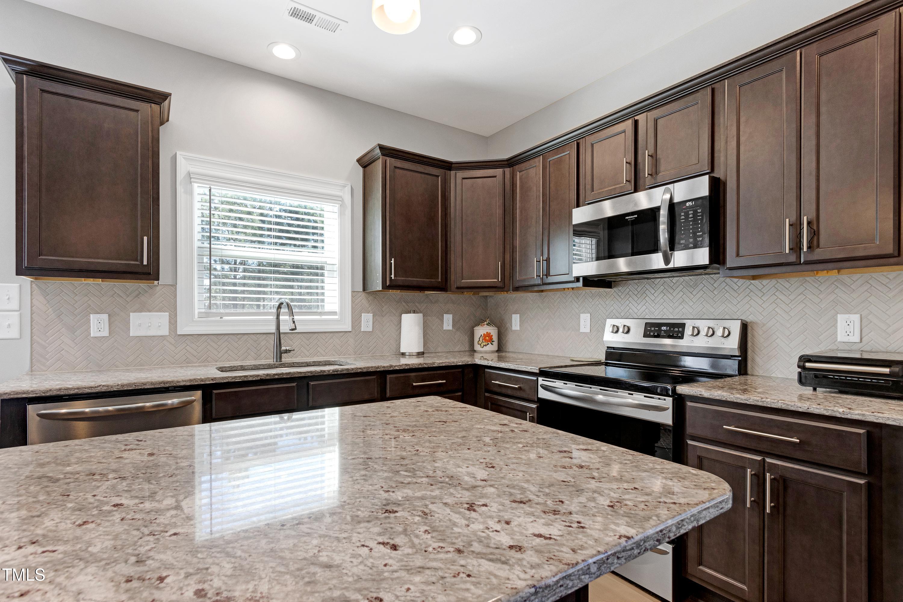 1613 Osprey Ridge Drive Willow Spring, NC 27592 - Photo 11 of 37 a kitchen with stainless steel appliances a stove sink microwave and cabinets