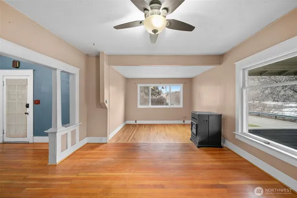 a view of an empty room with wooden floor and a window