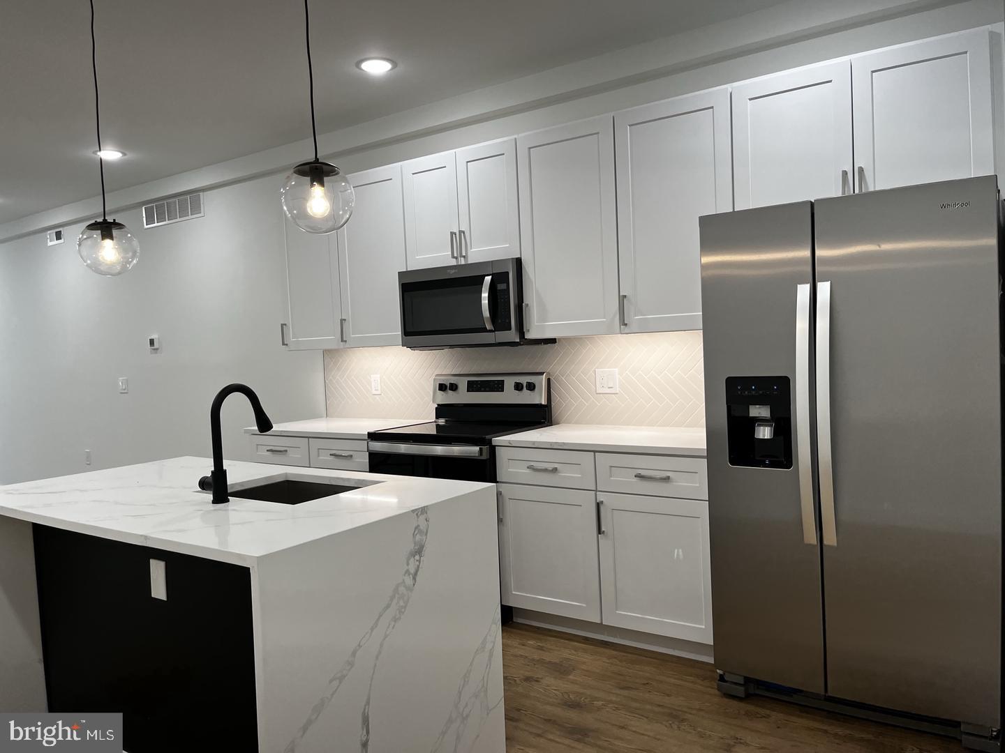 2117 North 8th Street Philadelphia, PA 19122 - Photo 3 of 17 a kitchen with stainless steel appliances granite countertop a refrigerator a sink a stove and white cabinets with wooden floors